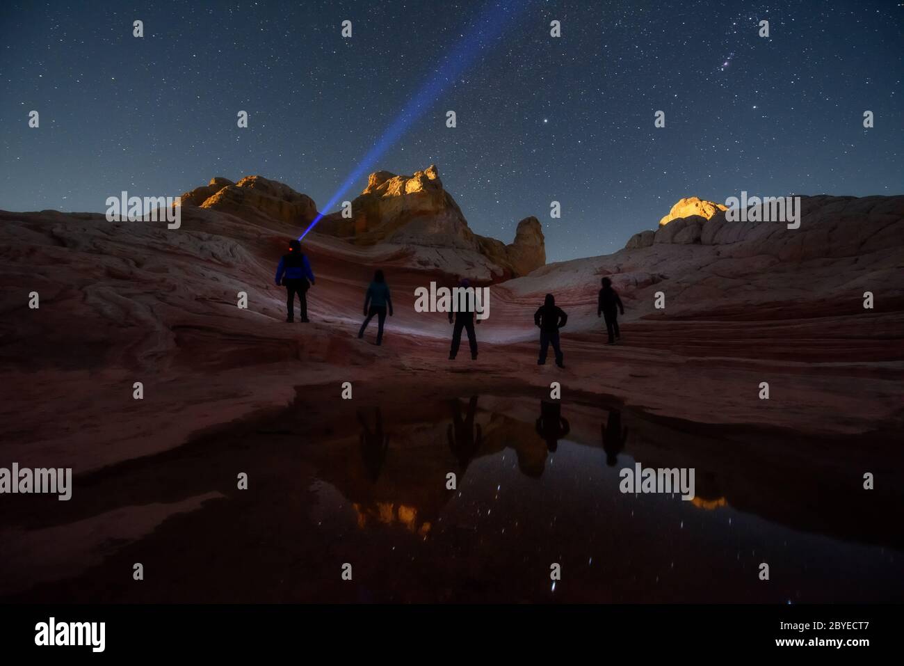 Group of stargazers posting under the night sky full of stars at White Pocket, remote area in Arizona desert. Inspring travel and adventure theme. Stock Photo