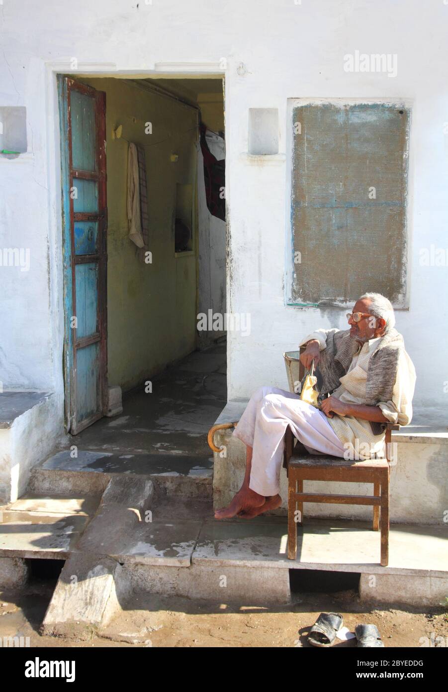 elderly Indian man sits outside his home Stock Photo