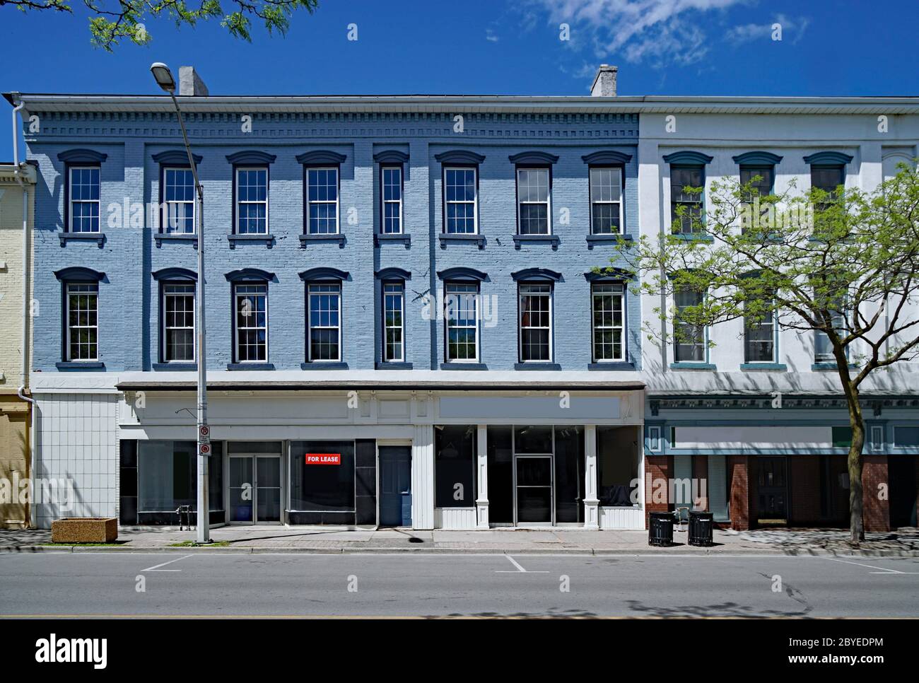 main street facade of old brick buildings with vacant stores at street level and apartments above Stock Photo