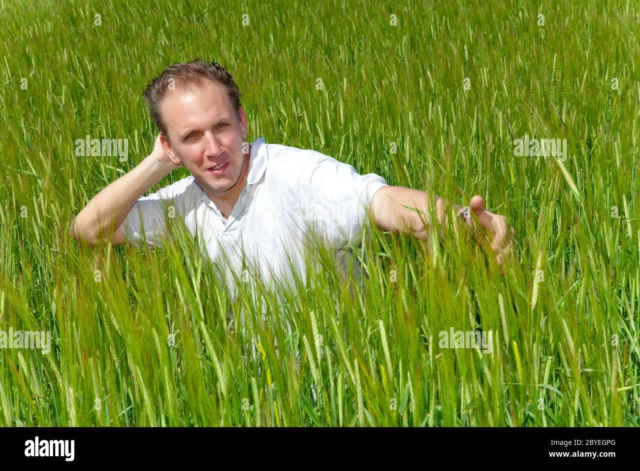 The happy young man in the field of green ears Stock Photo