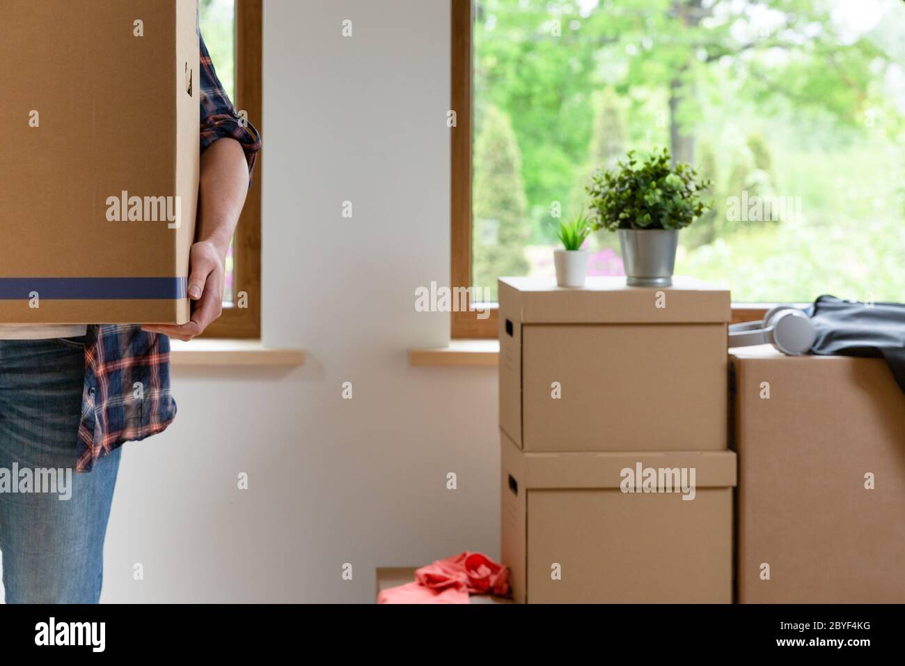 Move. Cardboard boxes for moving into a new, clean home. In a sunny day by a window in attic. Stock Photo