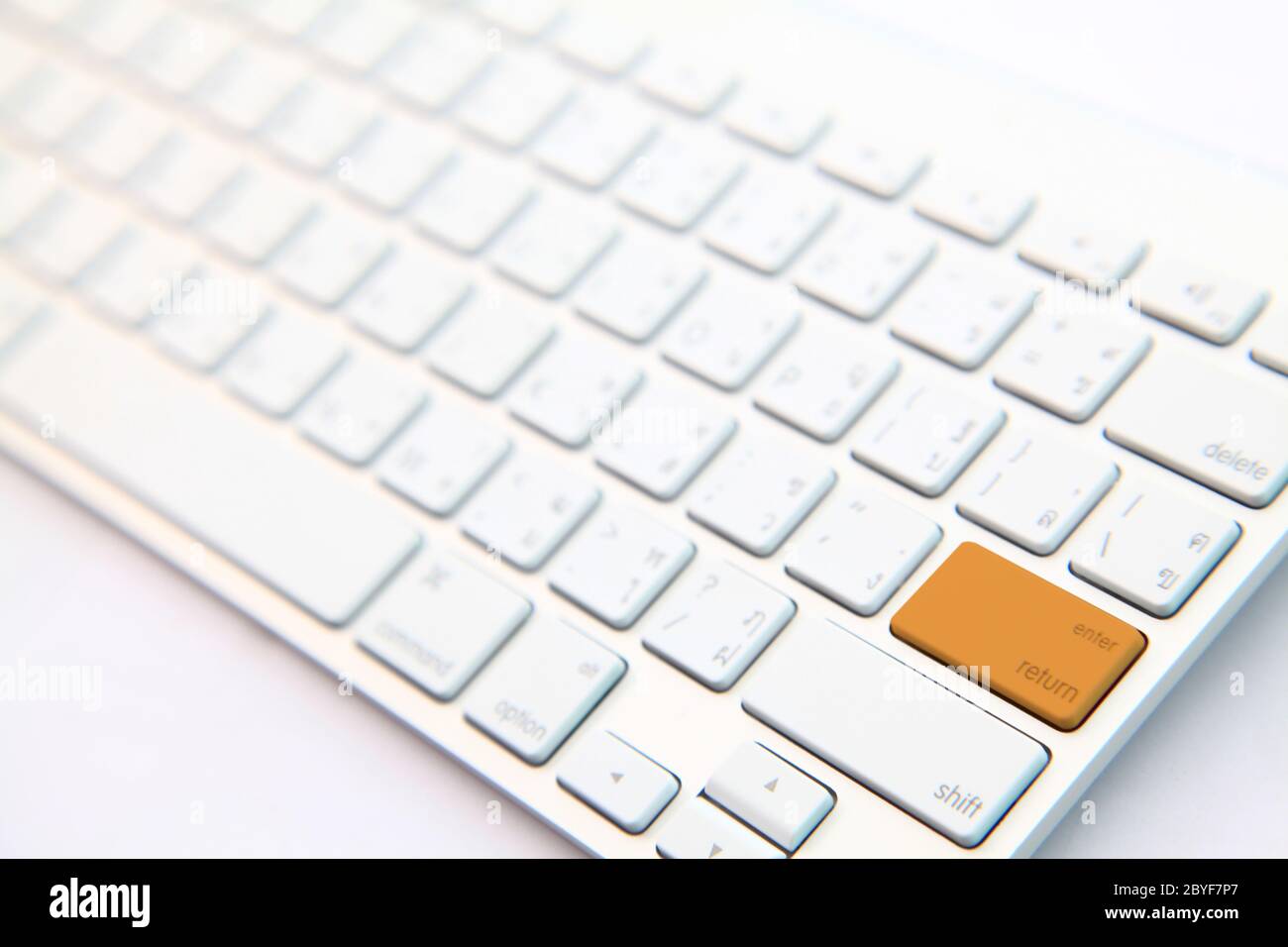 perspective of orange return button on white modern keyboard Stock