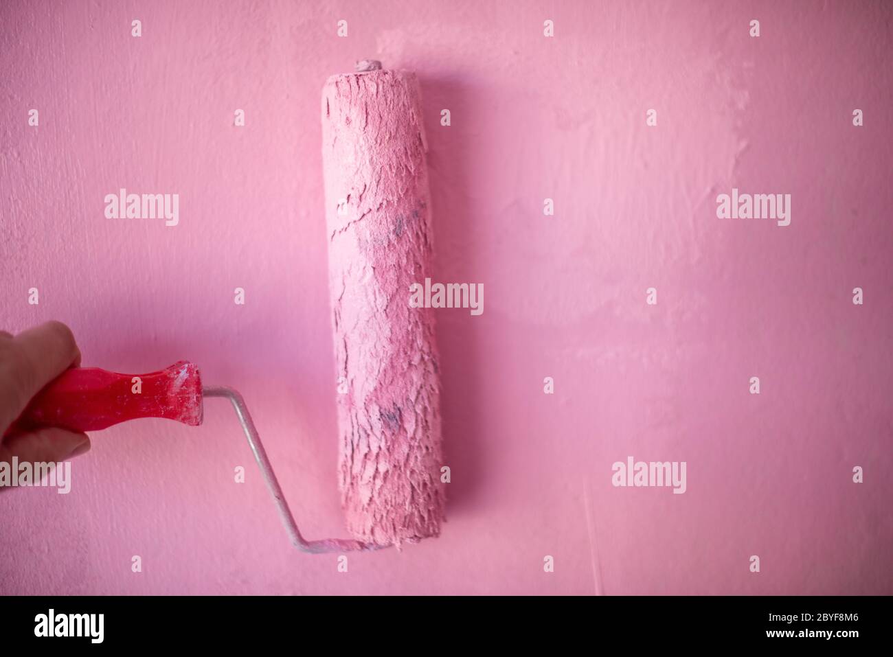 Paintbrush applying pastel colored paint to wall.  Stock Photo