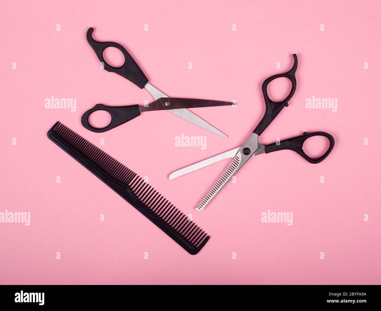 haircutting tools, scissors and comb on a pink background Stock Photo