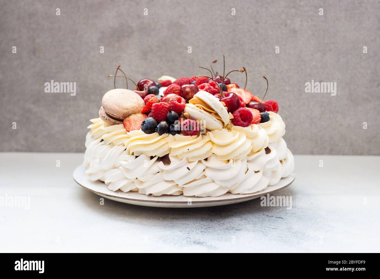 Big Pavlova Meringue Cake With Fresh Berries And Macaroons On Plain Grey Background Copy Space Stock Photo Alamy