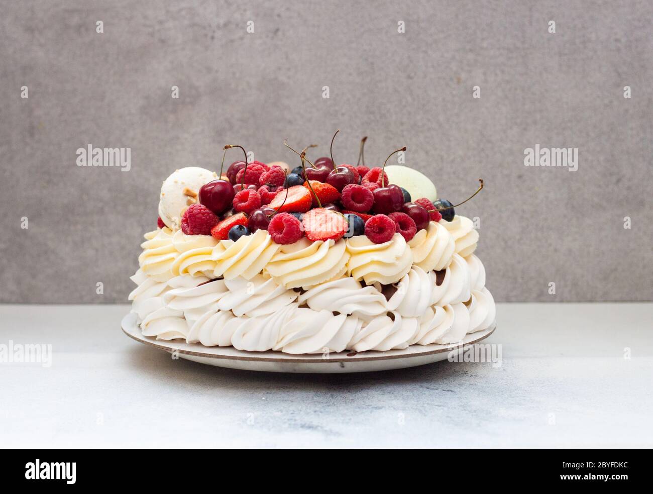 Big Pavlova Meringue Cake With Fresh Berries And Macaroons On Plain Grey Background Copy Space Stock Photo Alamy