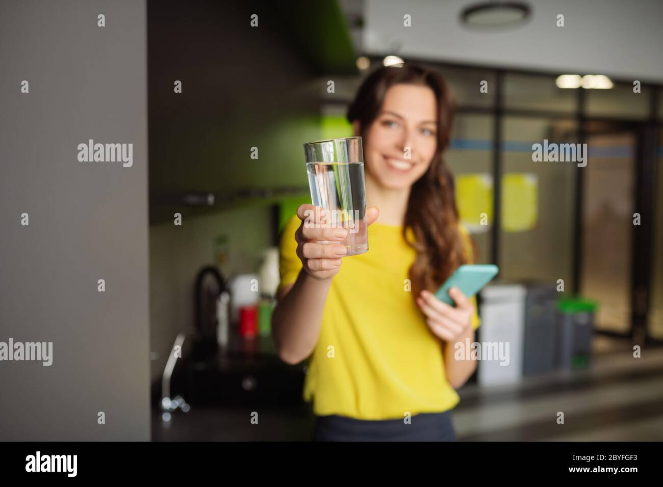 Beautiful slender girl holding a glass of water forward. Stock Photo