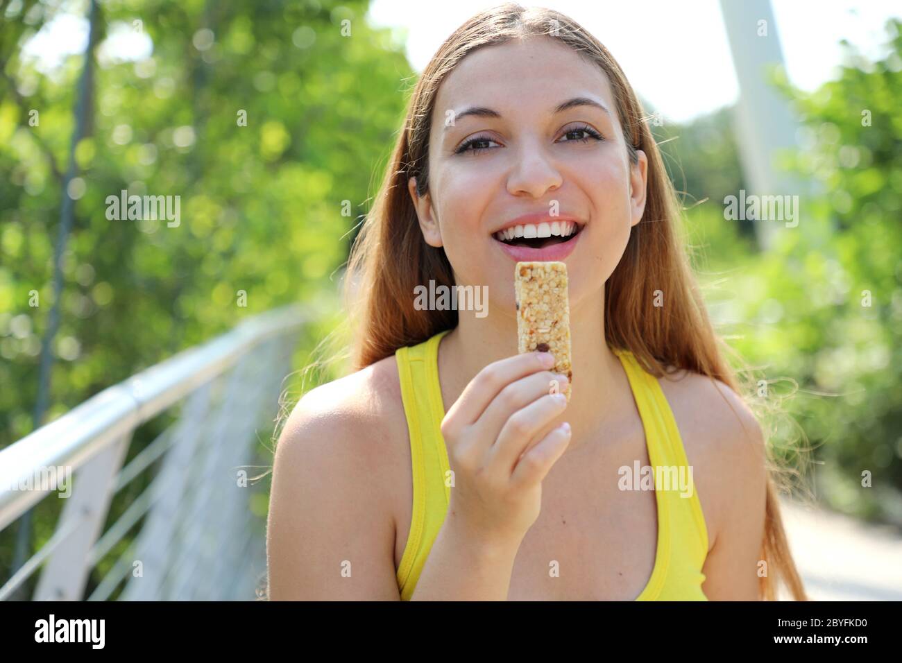 Fitness woman eating an energy bar looking at camera. Close up of
