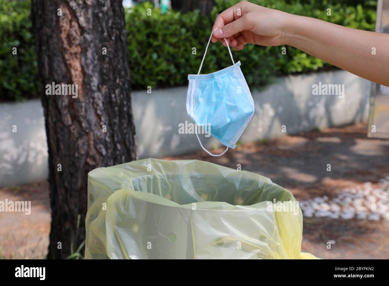 Throw surgical mask in public garbage can in city street. Hygienic mask  puts in the trash Stock Photo - Alamy