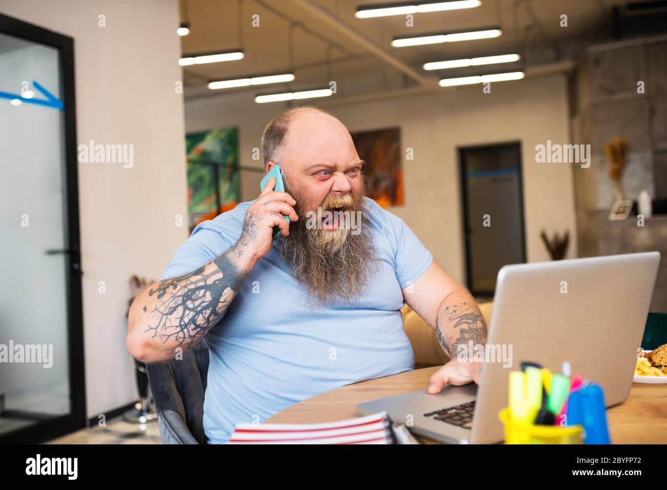 Bald man talking on the phone and looking angry Stock Photo