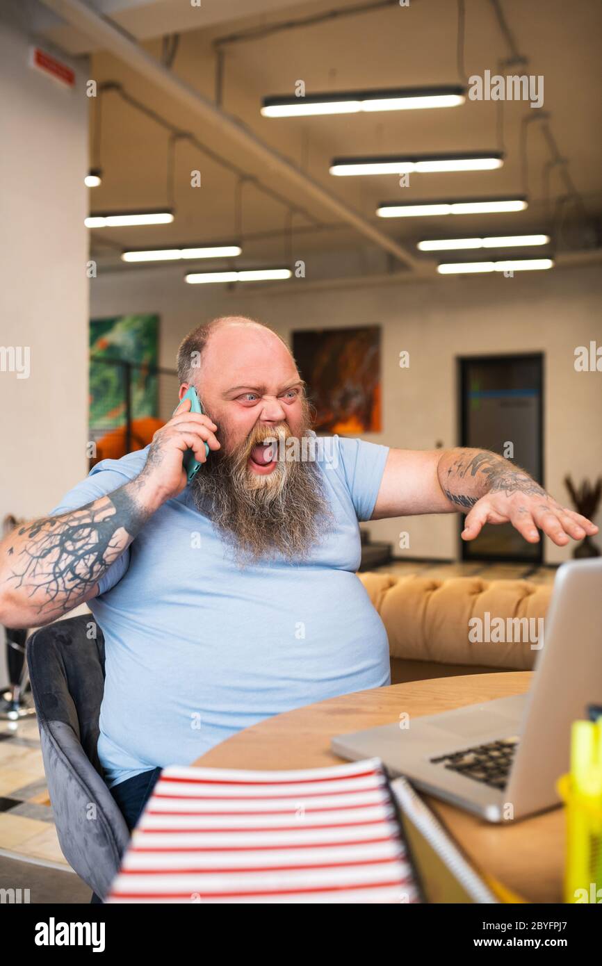 Bald man talking on the phone and shouting something with anger Stock Photo
