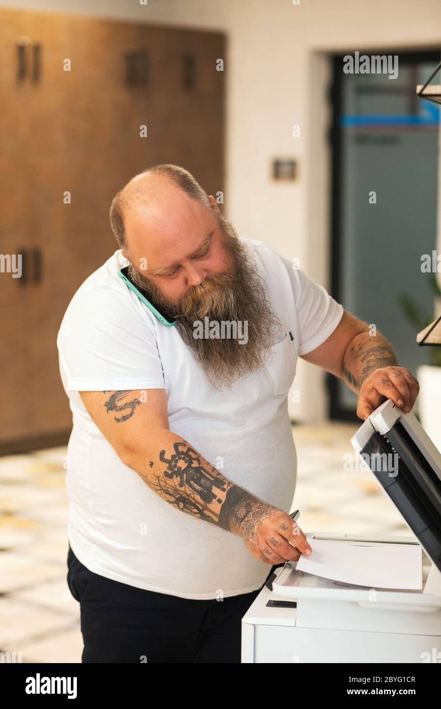 Bald bearded plus size man making copy on xerox Stock Photo