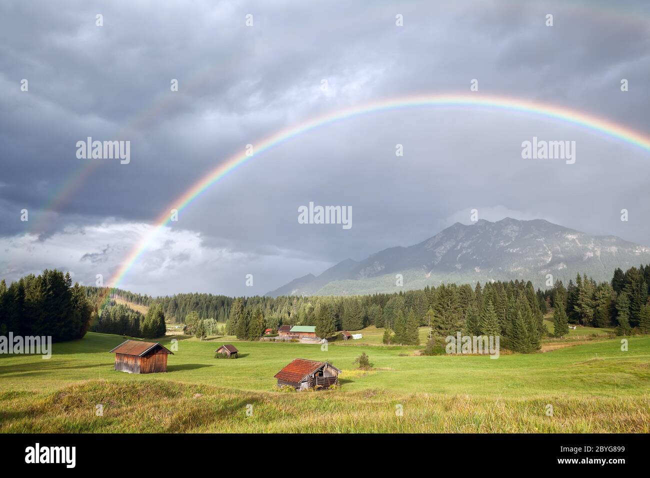 colorful rainbow over alpine meadows with wooden h Stock Photo