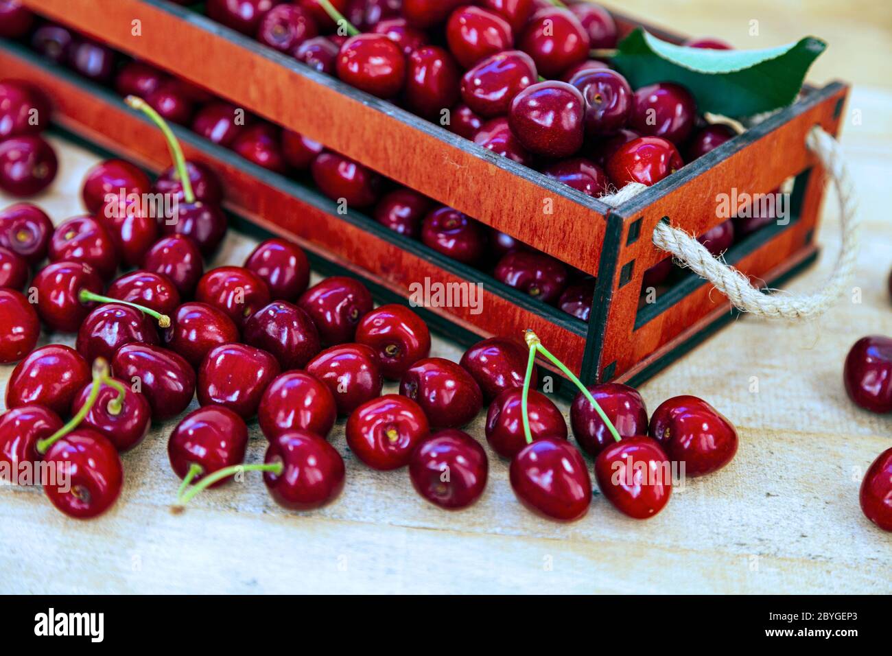 Ripe cherries in a box on a wooden background. Tasty berries. Still ...