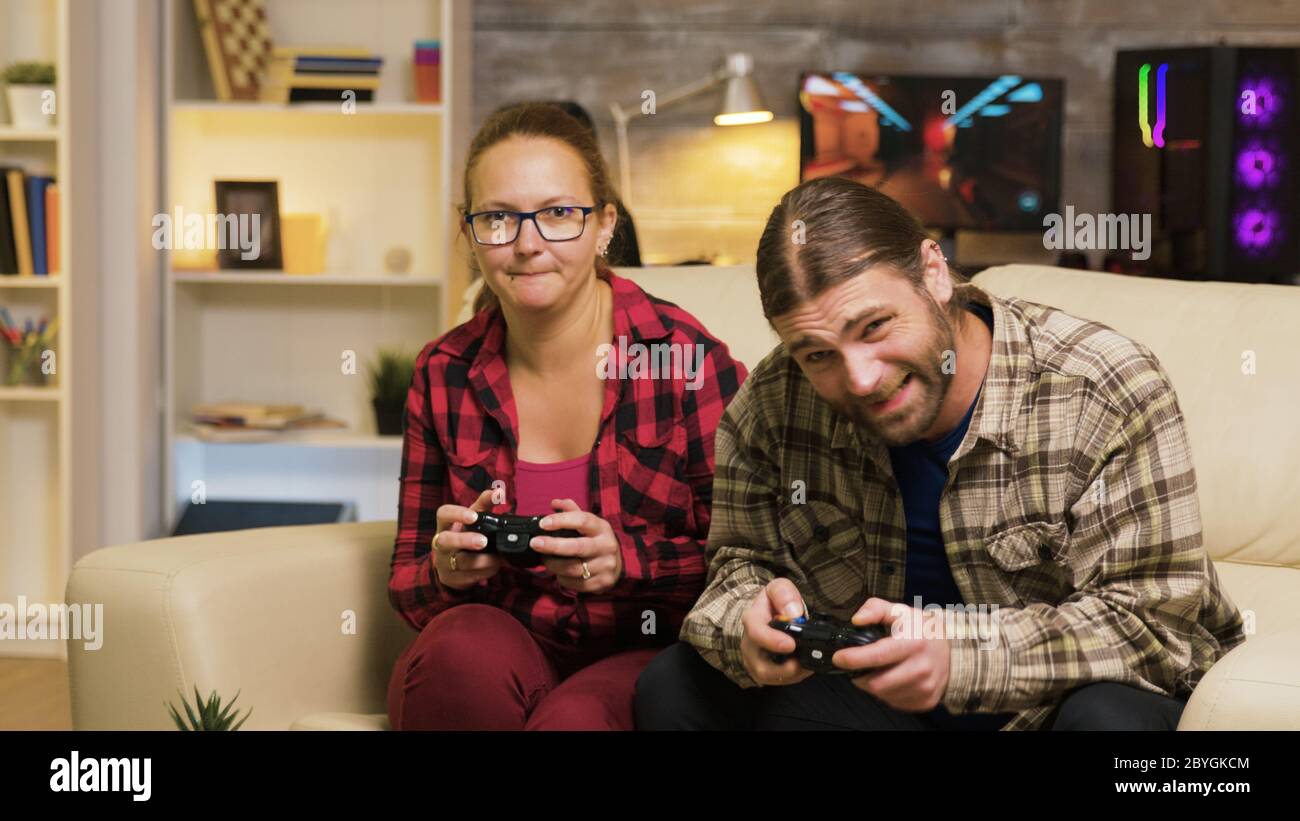 Woman yelling at her boyfriend after losing at video games sitting on couch. Man and woman playing video games. Stock Photo