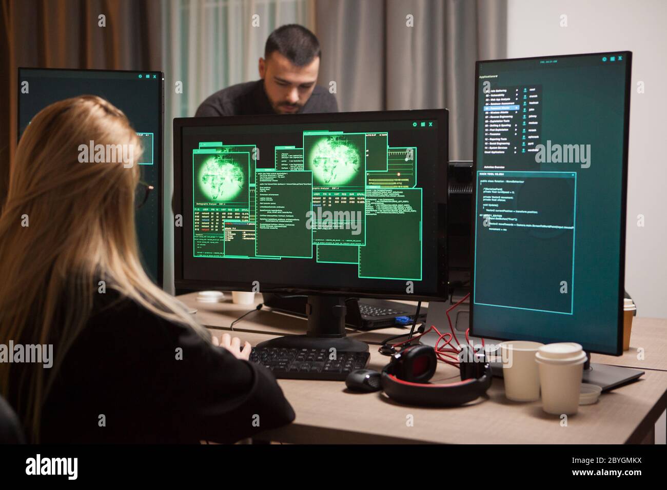 Blonde female hacker stealing secret information. Team on cyber criminals. Stock Photo