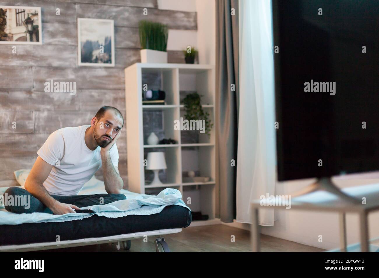 Bored man changing channels on tv late at night. Stock Photo