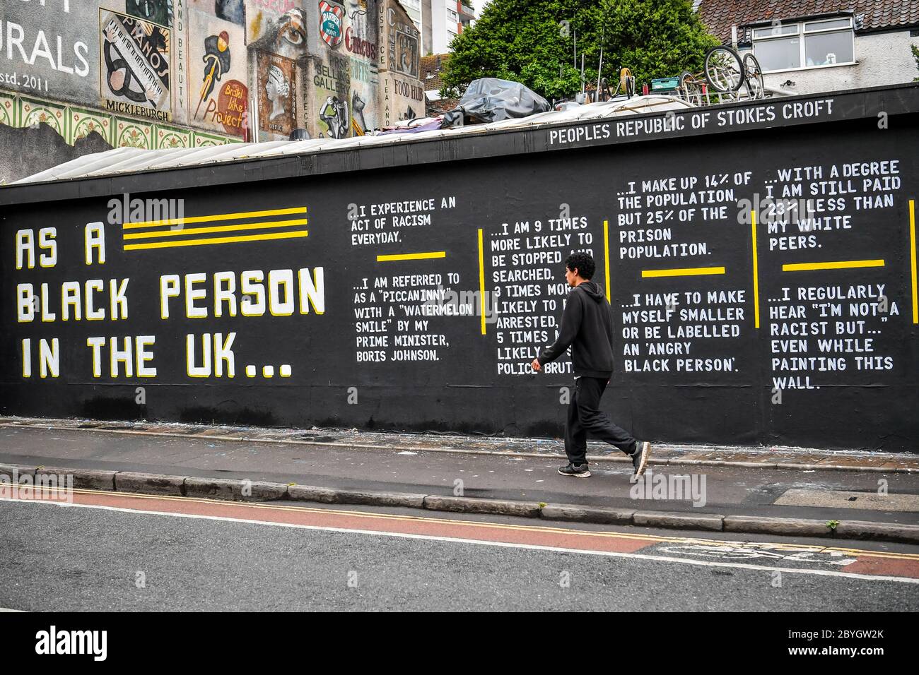 A man walks past a graffiti art piece on Black Lives Matter on a wall ...