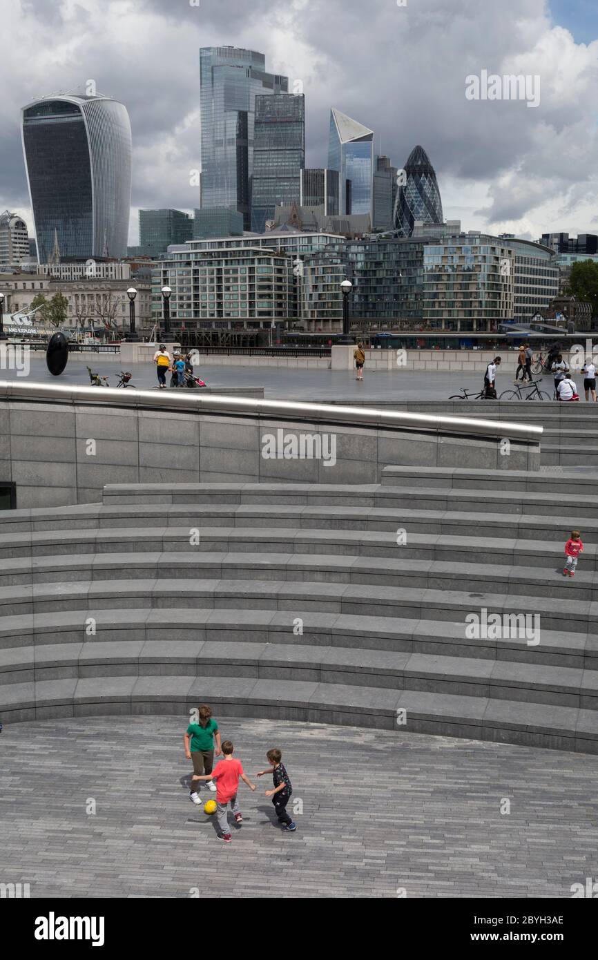 Young boys play football opposite the skyline of the City of London, the capital's financial district, during the UK's Conoriavirus pandemic lockdown, on 7th June 2020, in London, England. Stock Photo