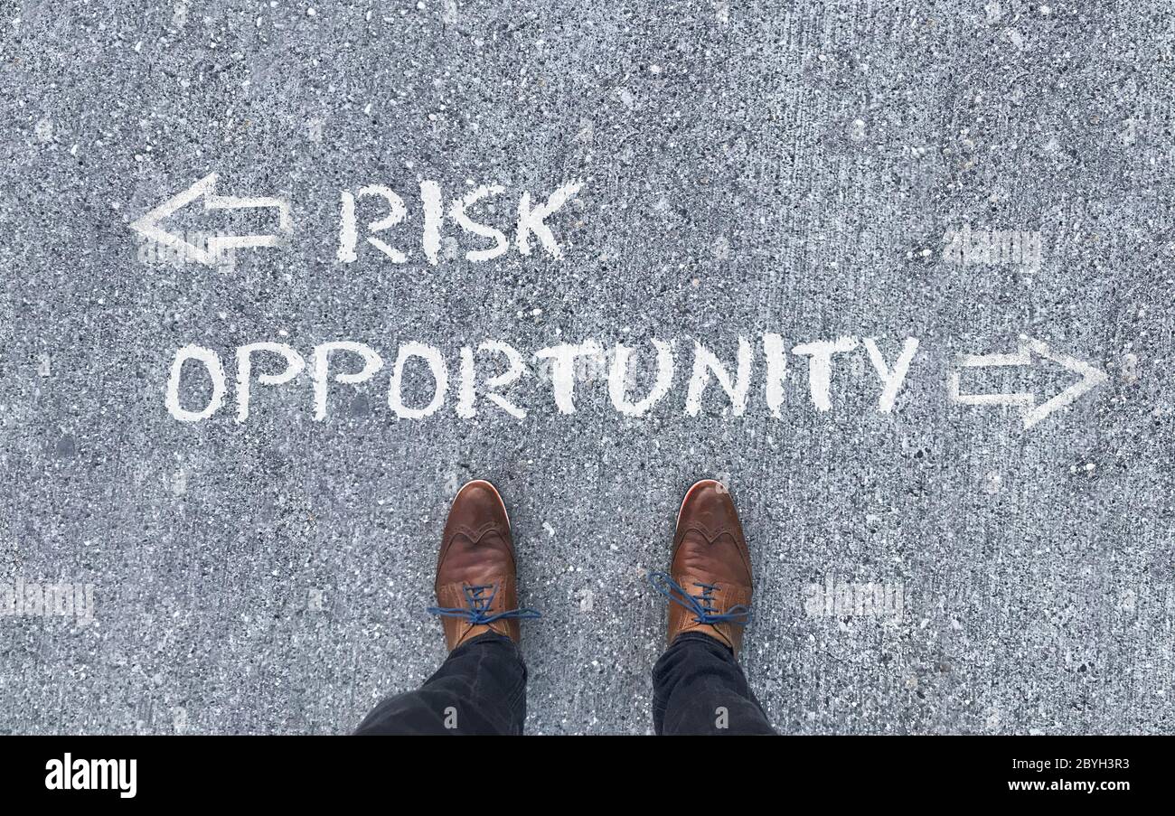 Top view on a man standing in front of the words 'Risk' and 'Opportunity' with arrows pointing to the left and right side of the picture Stock Photo
