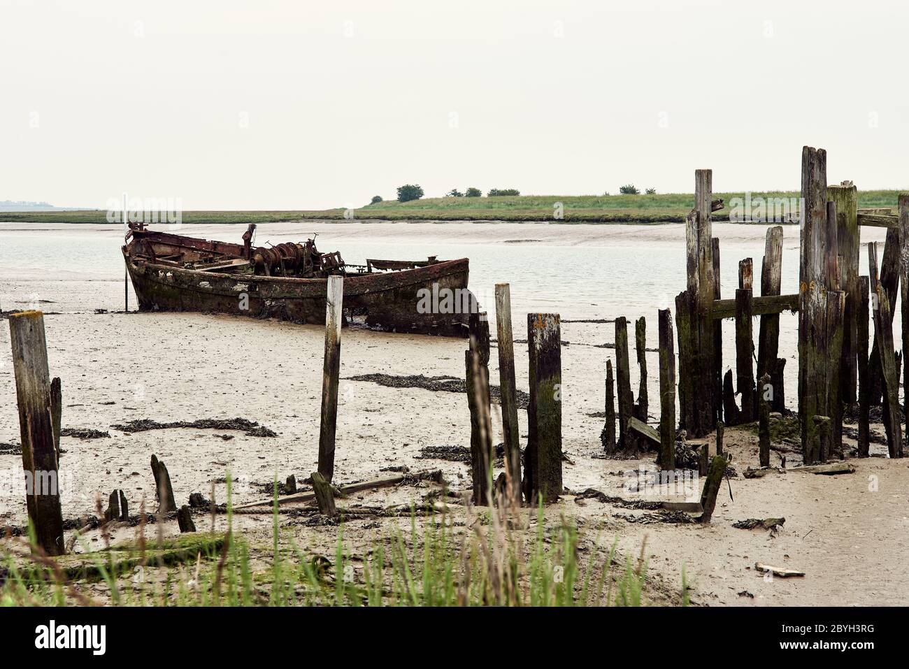 Derelict boat and jetty at low tide. Oare Creek, Faversham, Kent, UK Stock Photo