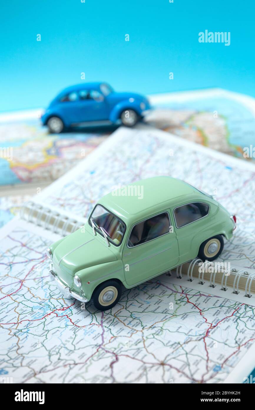 Two miniature classic cars driving through a road map. Space for text. Concept of travel and tourism by car. Stock Photo