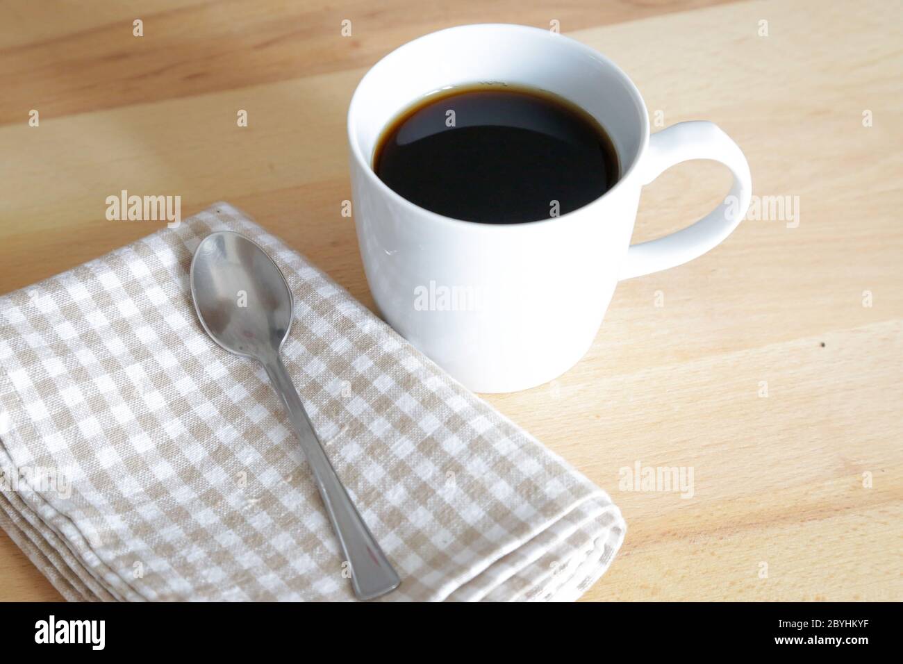 French croissant with a cup of black coffee as breakfast, natural light on wooden table Stock Photo