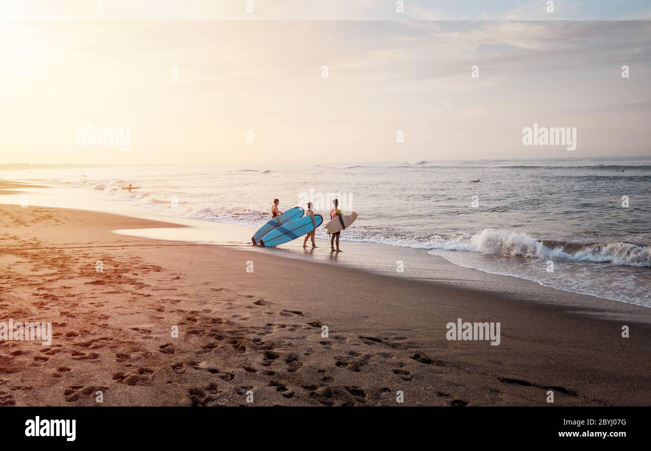 Bali / Indonesia - December 17, 2019: Beginners going to learn to surf during sunrise Stock Photo