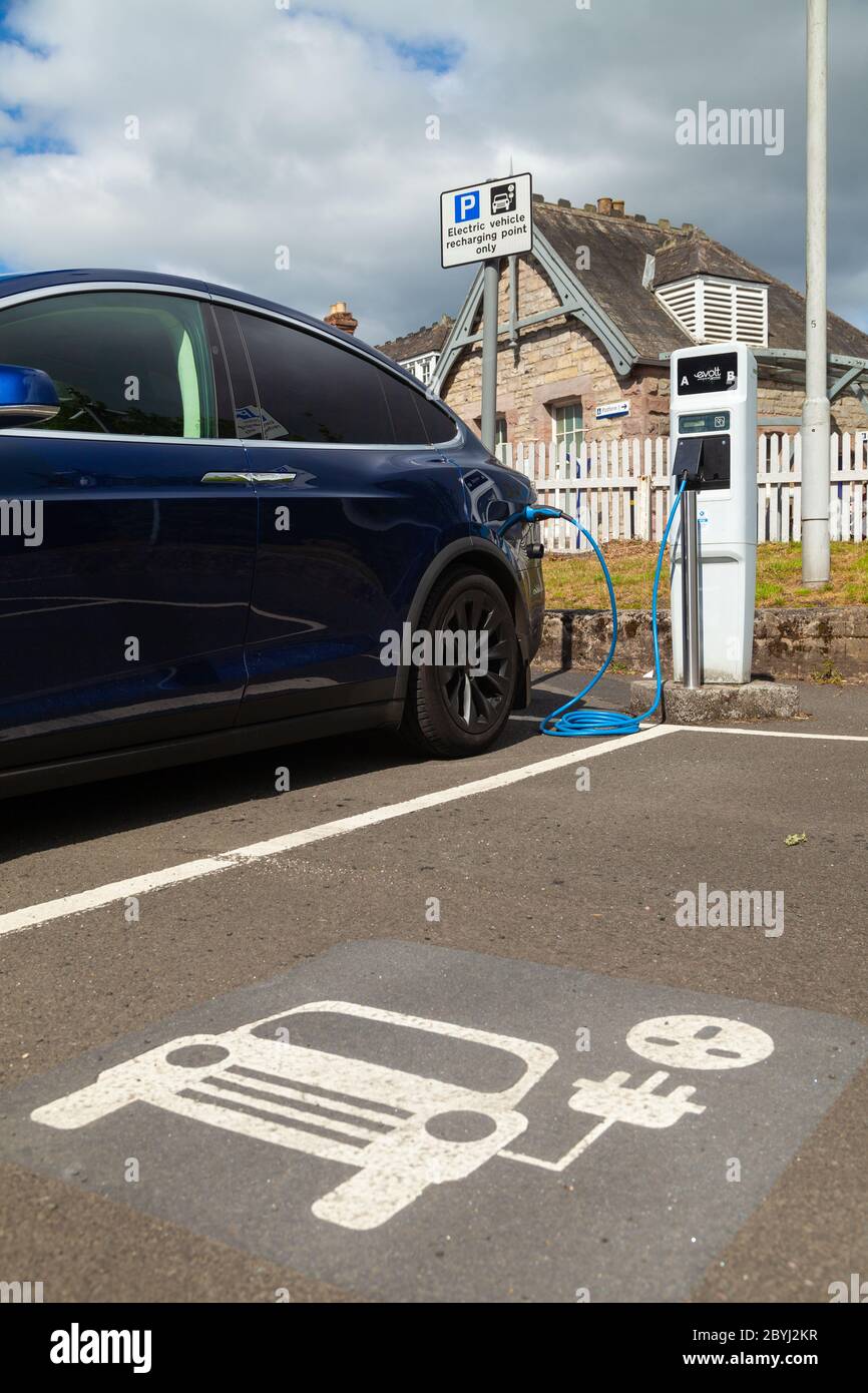 An electric Tesla car charging at a public charging station in Aberdour