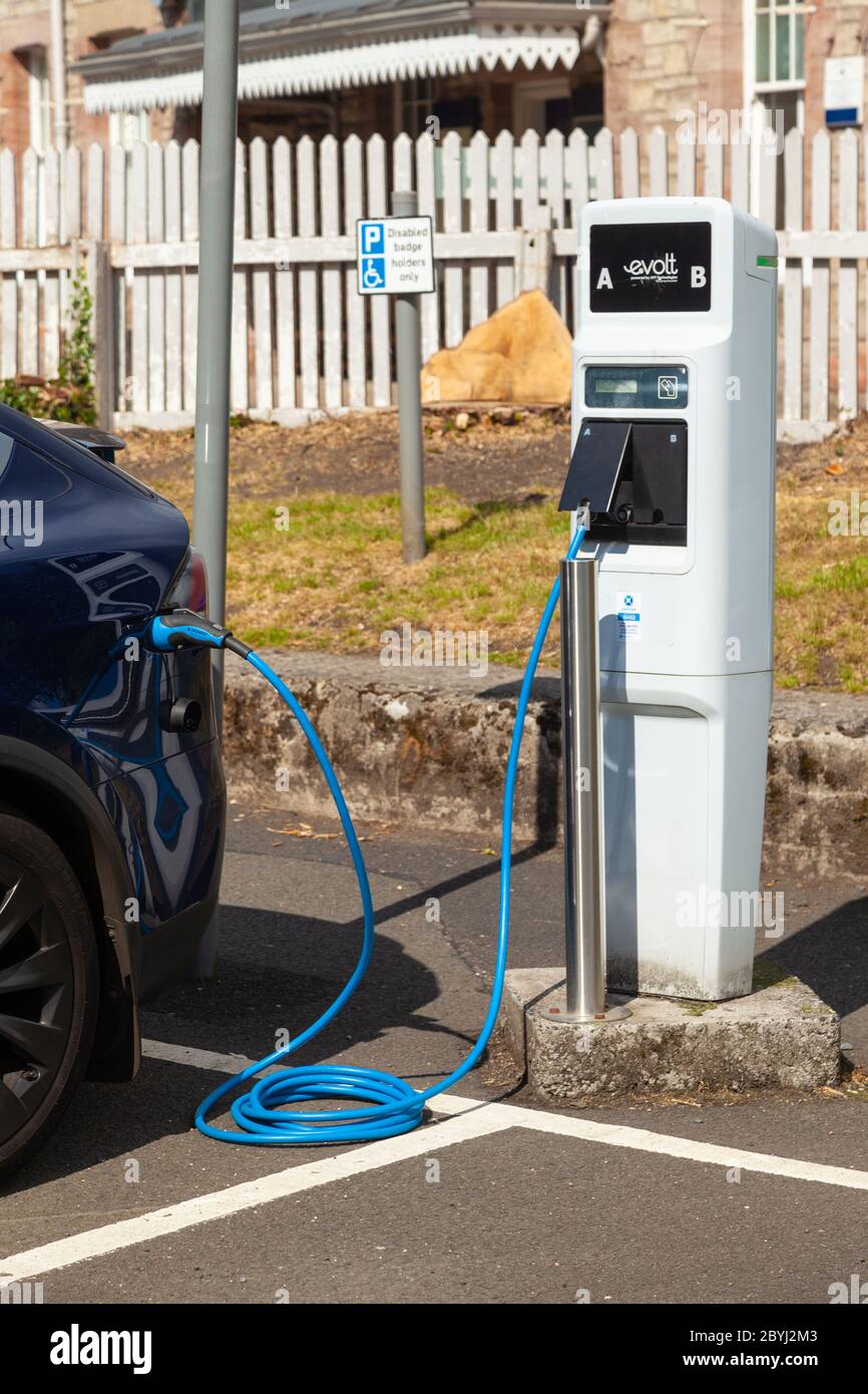 An electric Tesla car charging at a public charging station in Aberdour