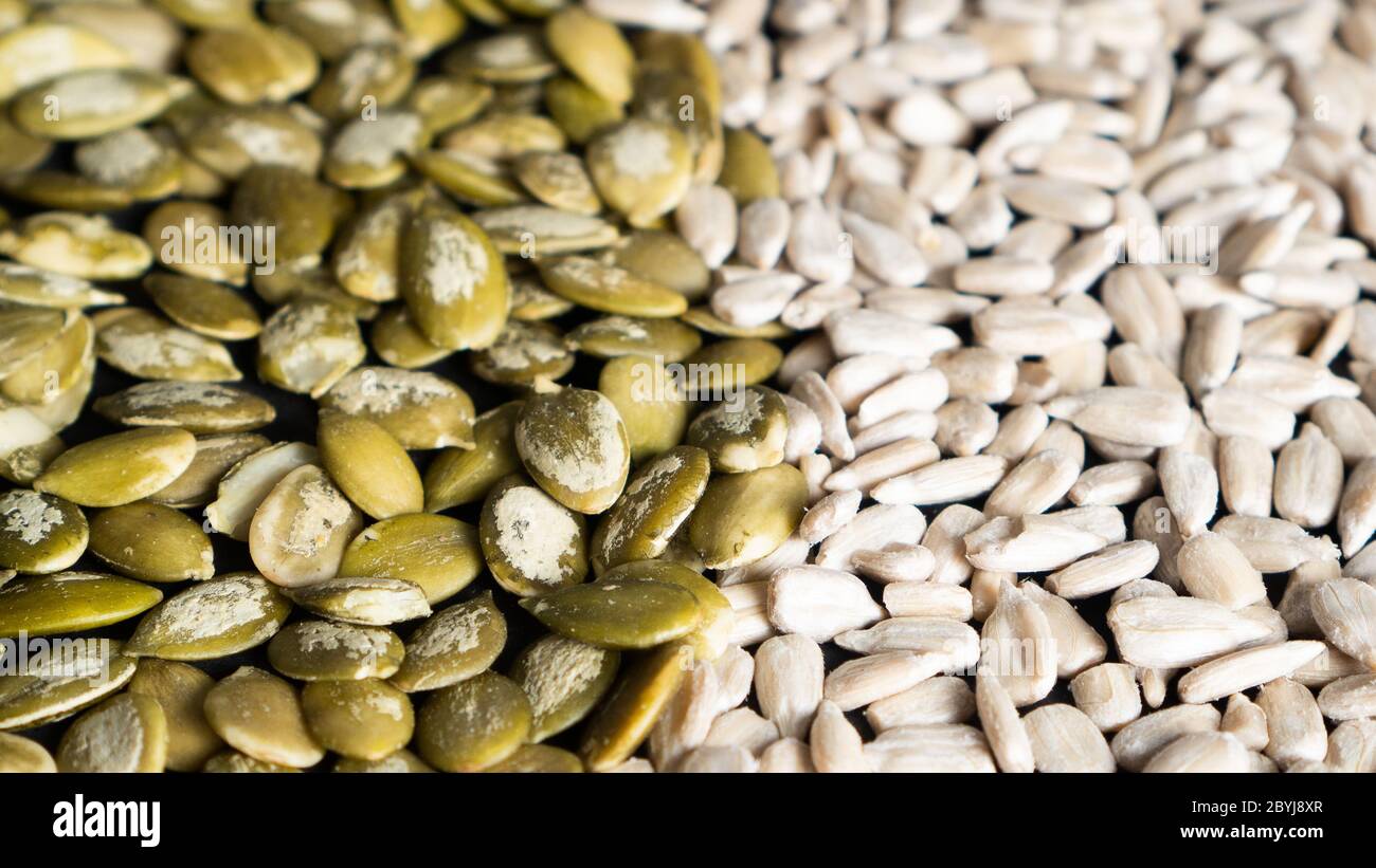 Top view of different seeds as a background. Two parts of sunflower and pumpkin seeds. Healthy food. Seeds texture Stock Photo