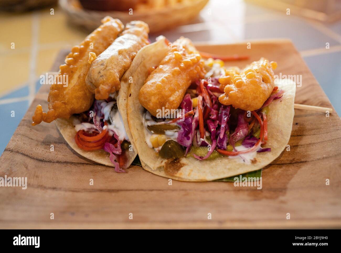 Freshly made of healthy vegan burger,  dish represented on wooden plate. Man's hands taking vegan burger from plate in vegan restaurant or cafe. Stock Photo