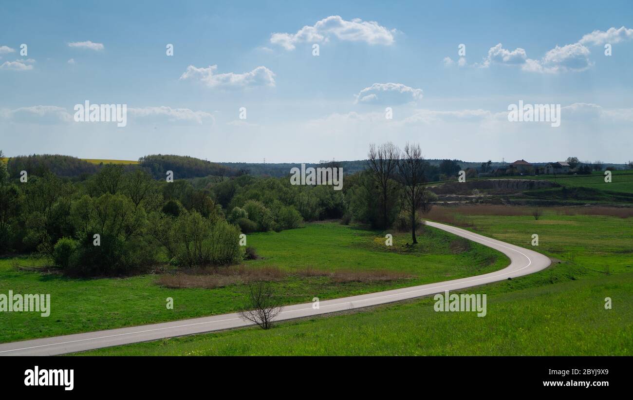 Countryside road in Ukraine. Green fields and blue sky. Winding country side road between meadows and trees. clear day Stock Photo