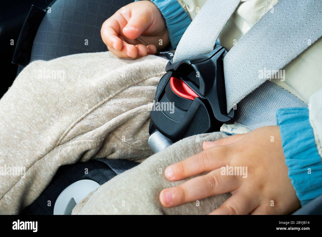 Little baby child fastened with security belt in safety car seat, close-up to the car seat lock Stock Photo