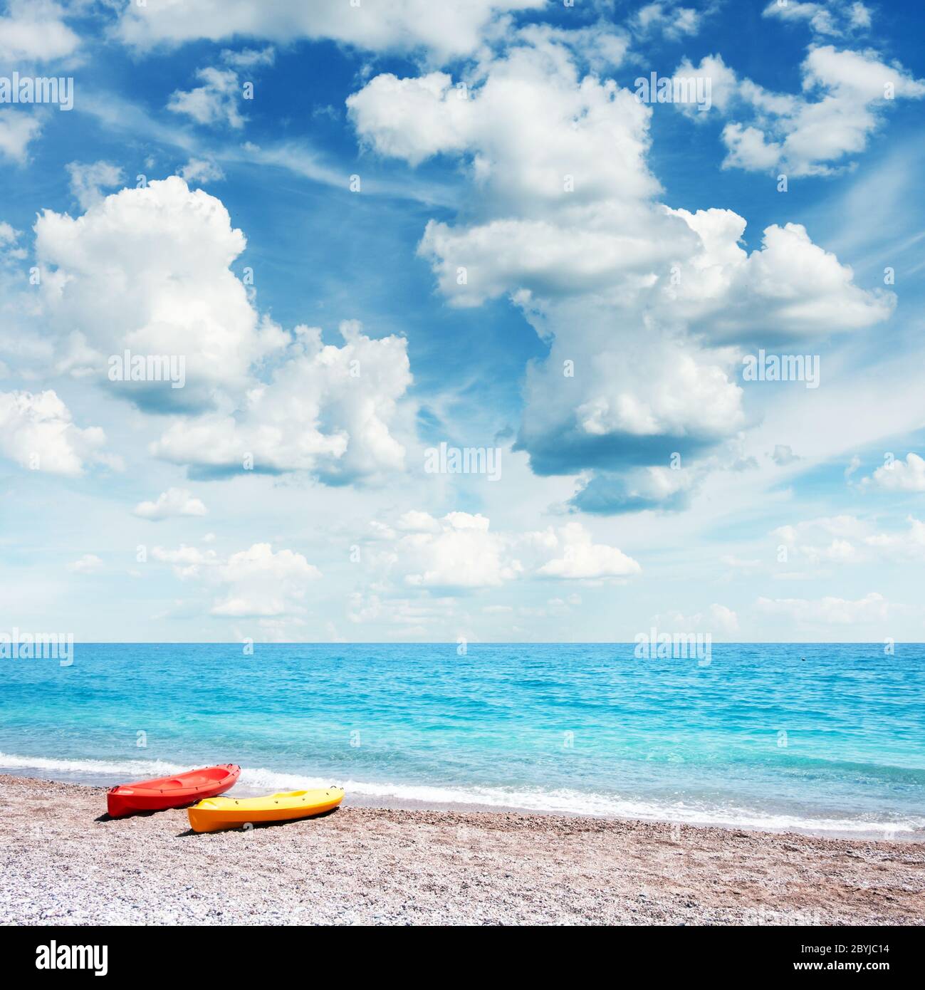 Two kayaks on sea edge. Incredible blue sky with fluffy clouds on background. Summer time Stock Photo