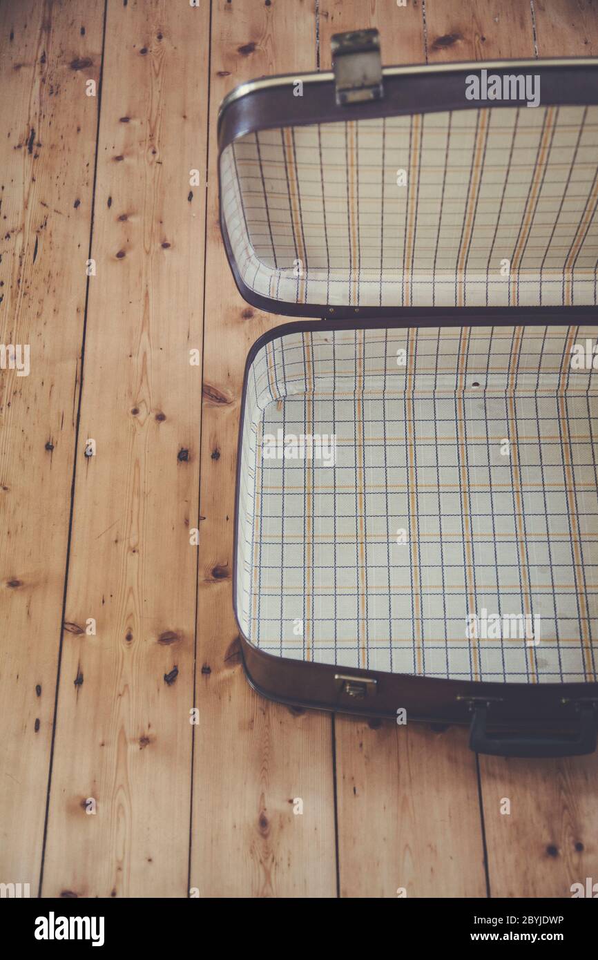 An open old vintage brown travel suitcase on a wooden floor Stock Photo
