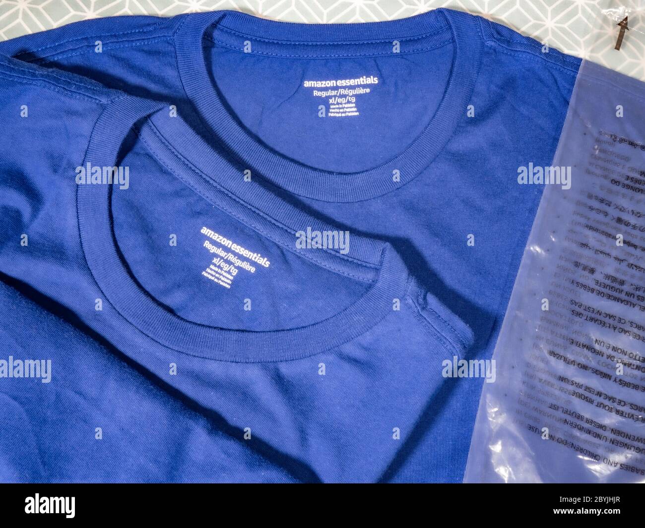 Two newly opened Amazon Essentials mid blue, plain tee shirts and their  plastic packaging - from Amazon's basic, low cost range of clothing Stock  Photo - Alamy