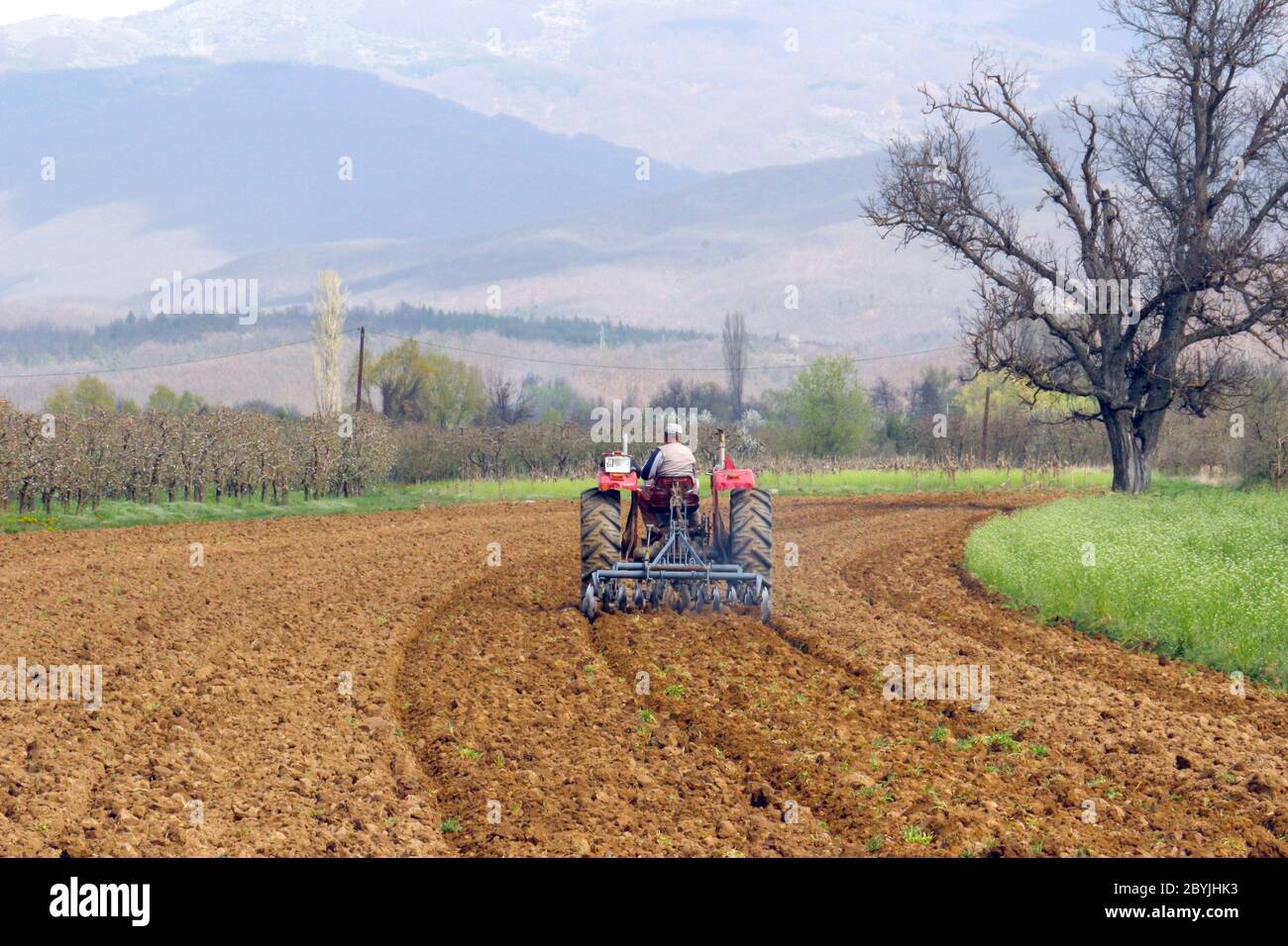 pictureof a man in tractor plowing field in spring Stock Photo - Alamy