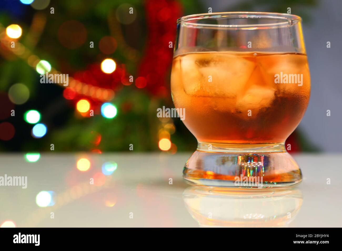 whiskey with ice against festive lights background Stock Photo