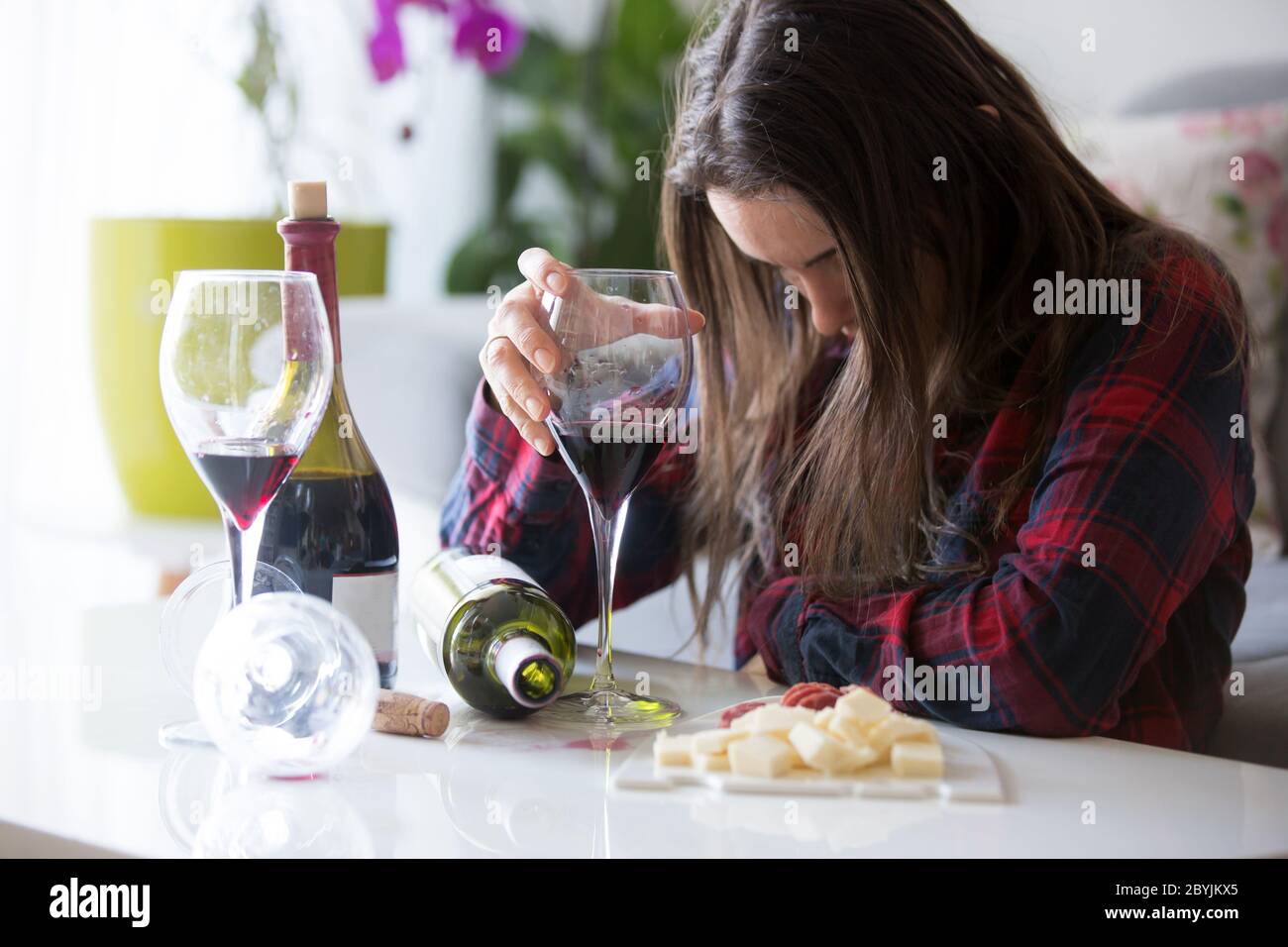 Sad tired woman, drinking wine at home, alone, sitting on the floor in