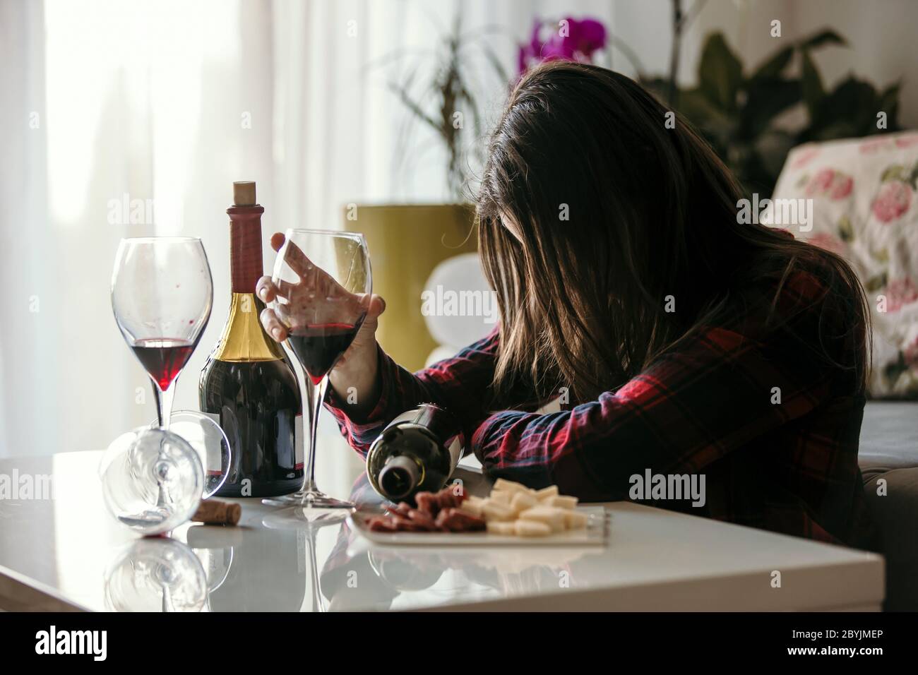 Sad tired woman, drinking wine at home, alone, sitting on the floor in