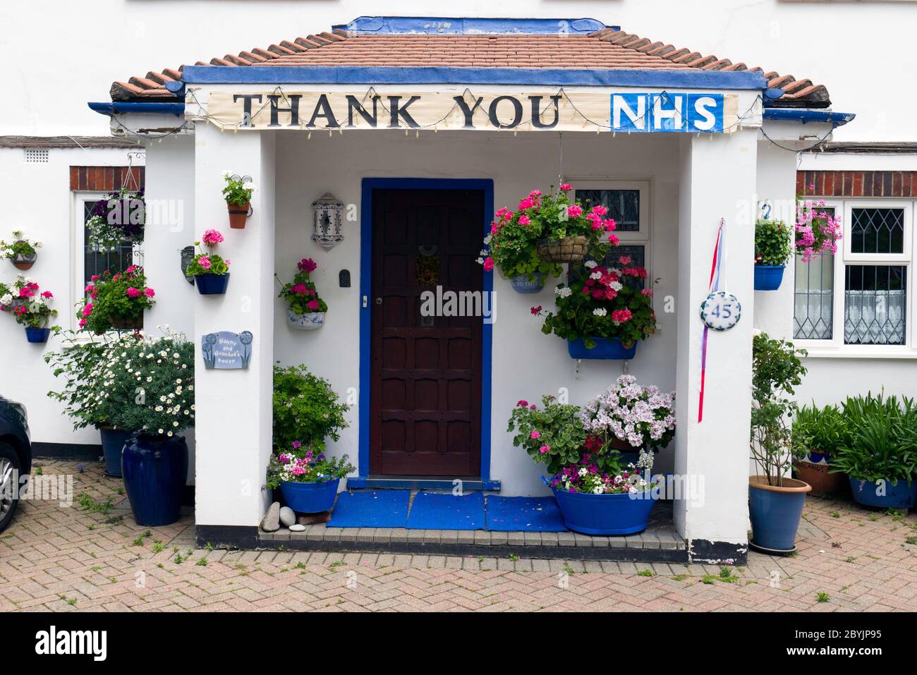 A sign saying Thank You NHS hanging above the porch of a Suburban House with colourful hanging baskets in. South West London. Stock Photo