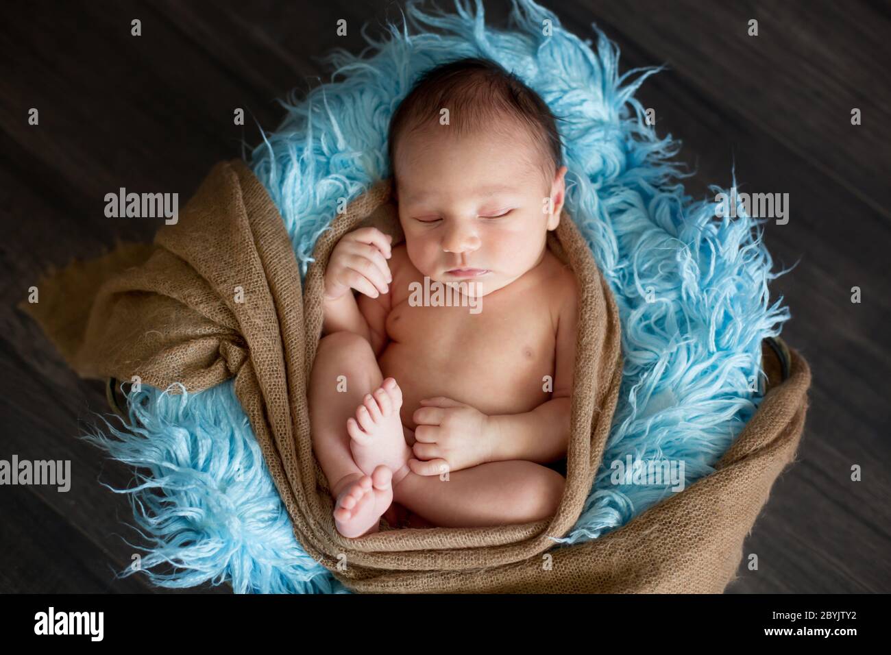 Cute little newborn baby boy, sleeping in basket with colorful ...