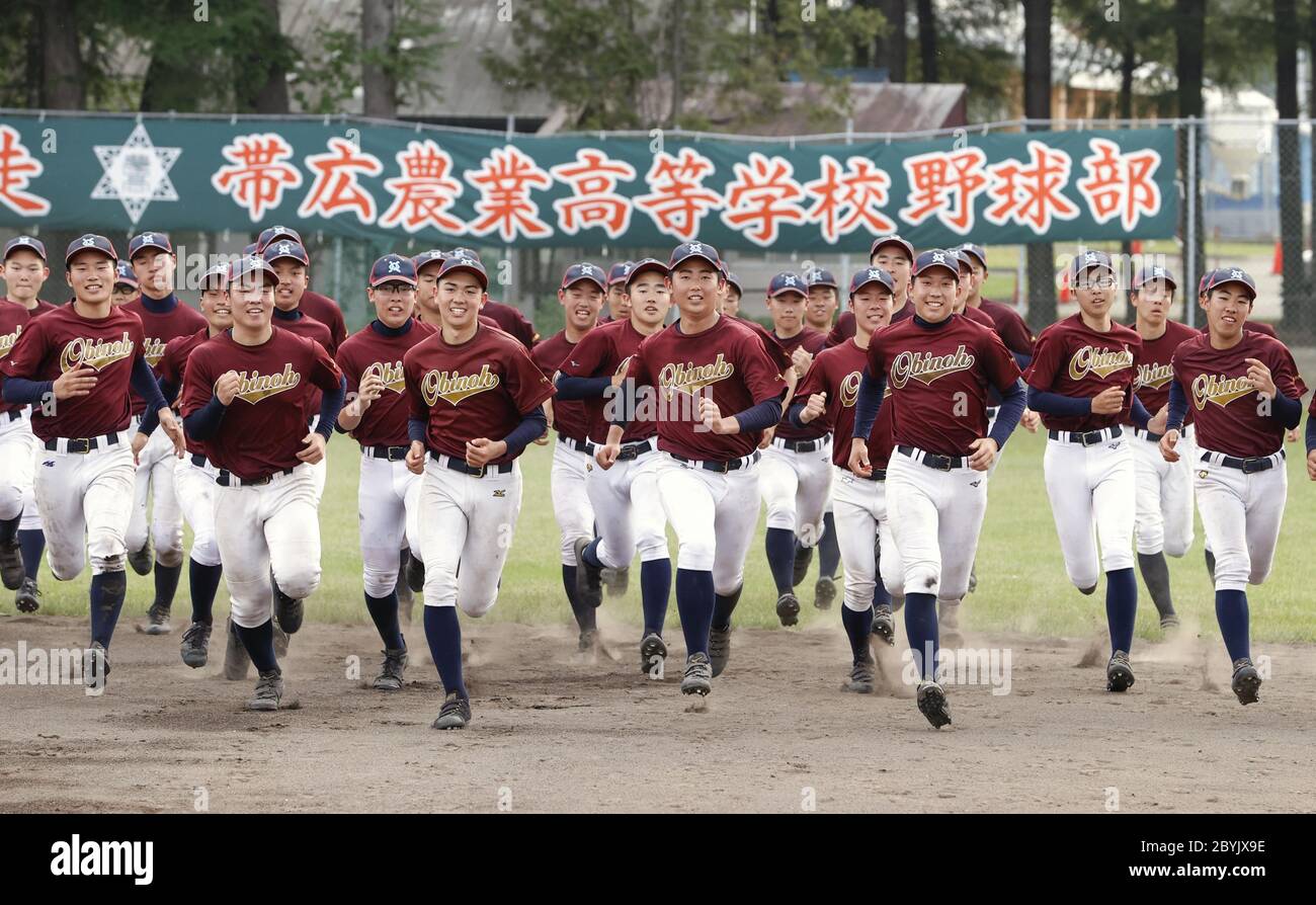 Baseball club members of Obihiro Agriculture High School run smiling at  their ground in Hokkaido on June 10, 2020, as they hear that the team will  be able to play at Koshien