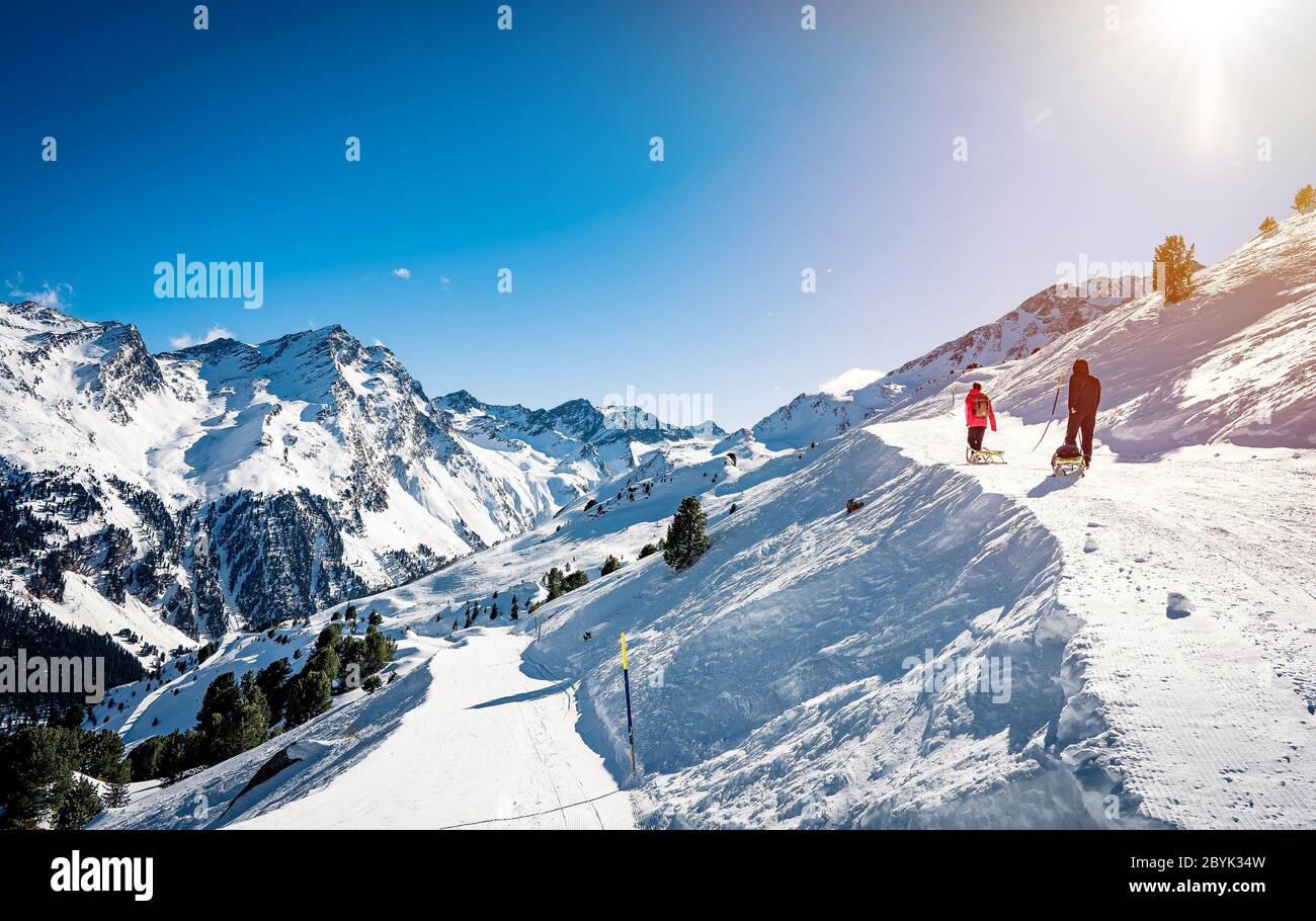 Experienced man hiker wanderlust during sunset. Standing against amazing high winter mountains. Rear view of tourist travels in beautiful Alps Stock Photo