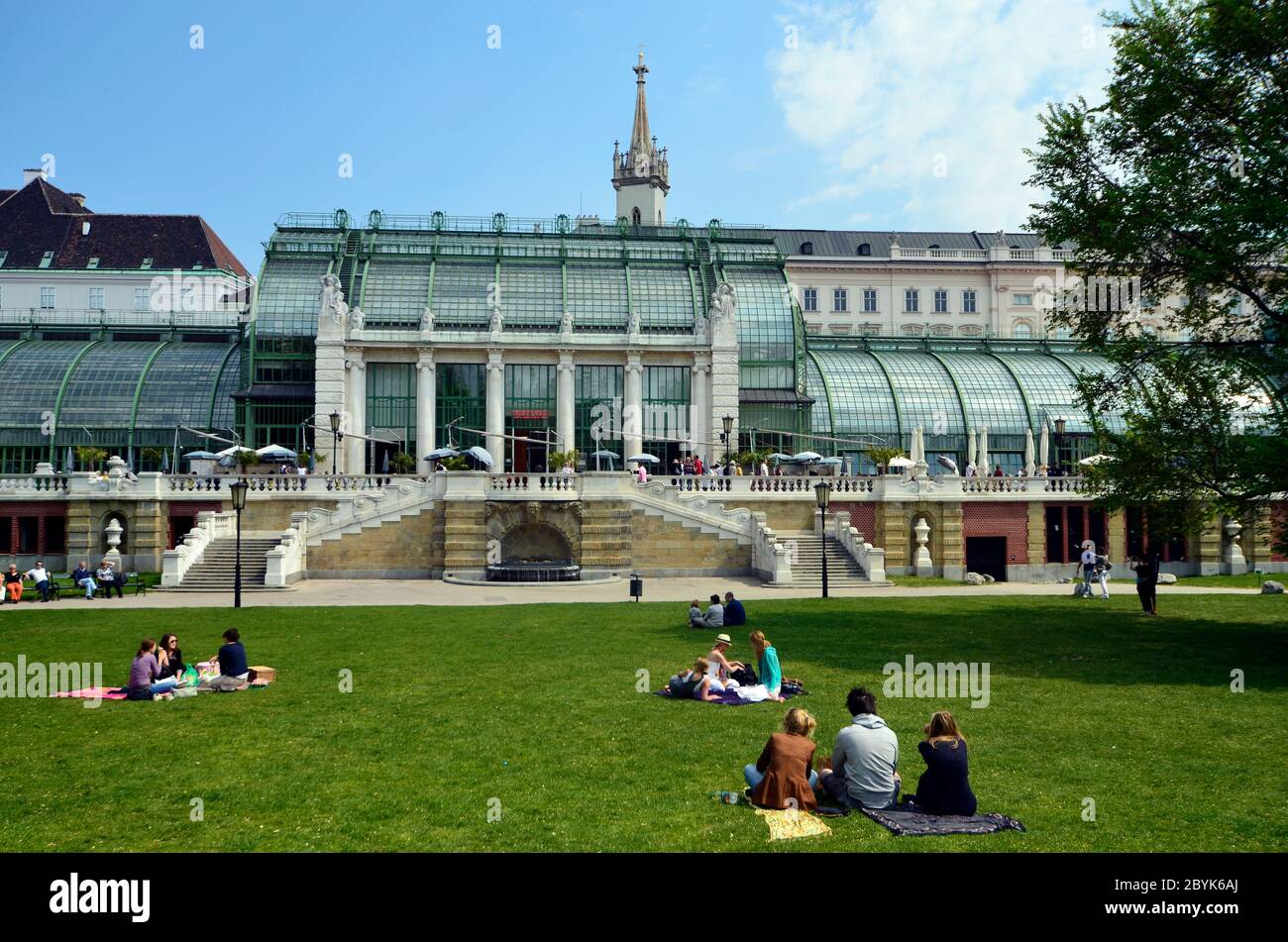 Vienna, Austria - April 24th 2011: unidentified people take a picnic in the grass of the public Burggarten with view to the new renovated palm house a Stock Photo