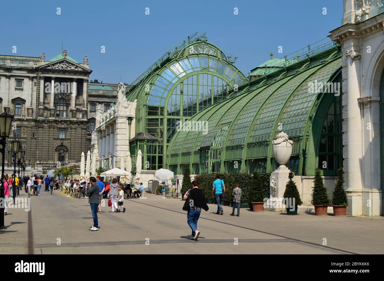 Vienna, Austria - April 24th 2011: unidentified people walk and take a rest in the new renovated palm house cafe in public Burggarten, with Hofburg bu Stock Photo