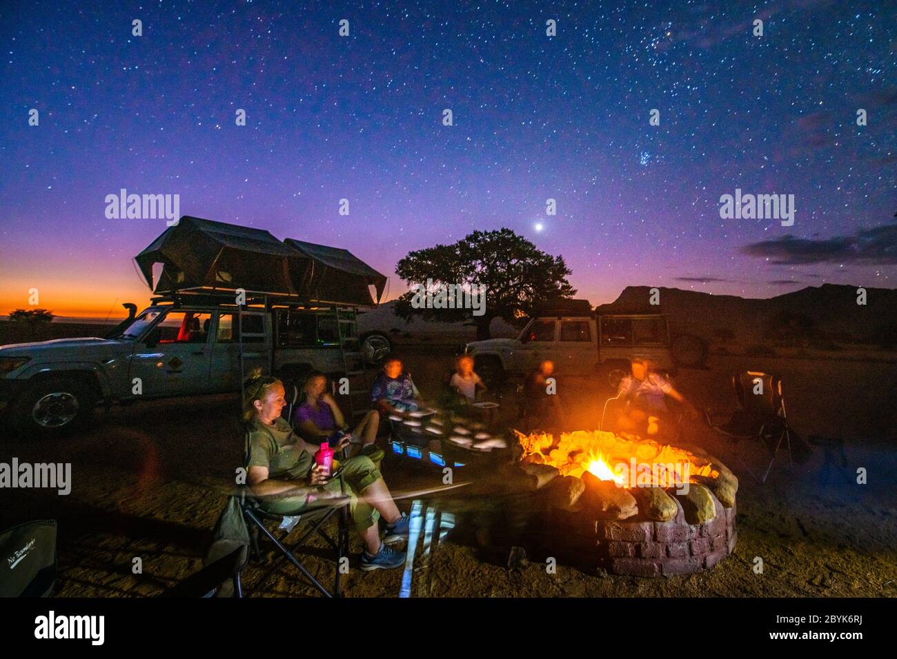 Everyone gathered around the fire under the glow of the stars , Helmeringhausen, Namibia Stock Photo