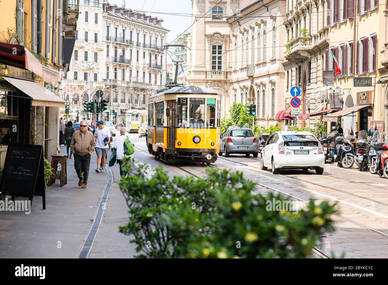 Milan. Italy - May 21, 2019: Old Yellow MIlan Tram. Street Panorama with Pedestrians and Cars on a Sunny Day. Stock Photo