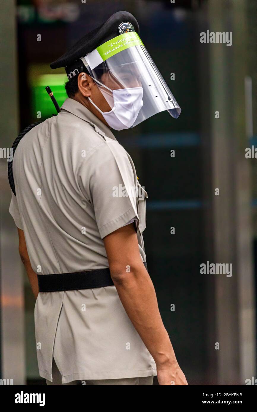Security guard at building entrance with face mask and plastic shield